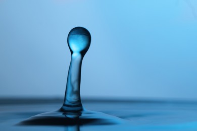 Photo of Splash of clear water with drop on light blue background, closeup