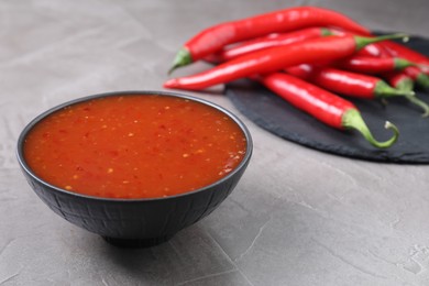 Photo of Spicy chili sauce in bowl on grey table. Space for text