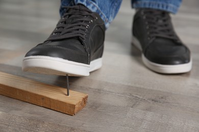 Careless man stepping on nail in wooden plank, closeup