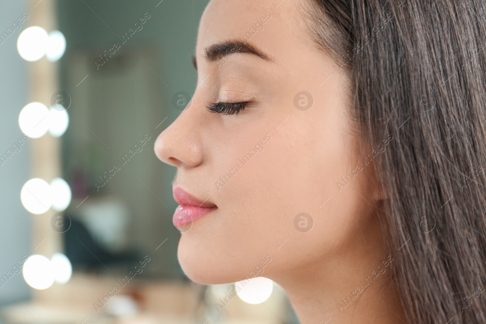 Photo of Attractive young woman with beautiful eyelashes on blurred background