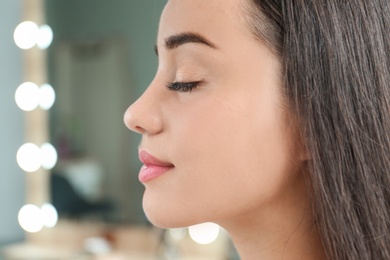 Photo of Attractive young woman with beautiful eyelashes on blurred background