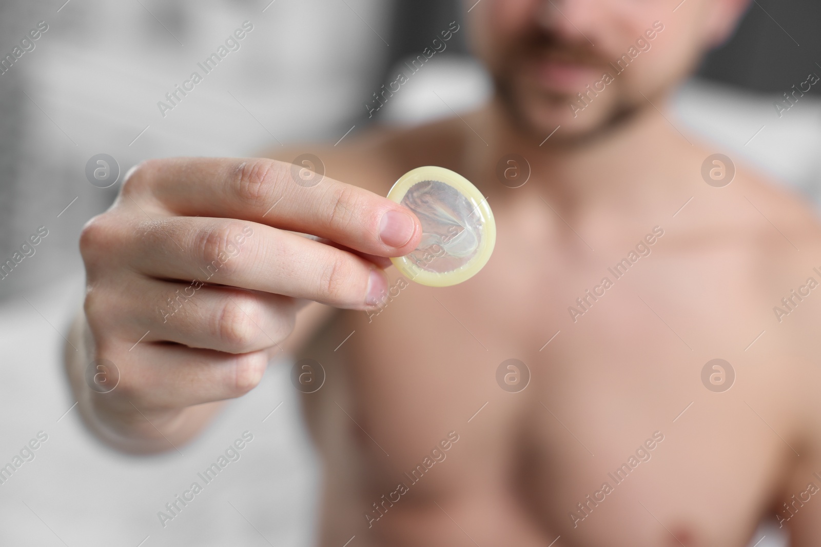 Photo of Closeup view of man showing condom on bed