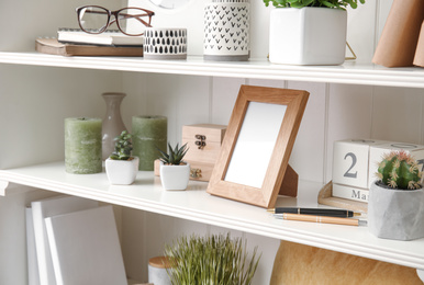 Photo of White shelving unit with plants and different decorative stuff