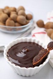 Photo of Bowl of tamarind sauce and fresh pods on light table
