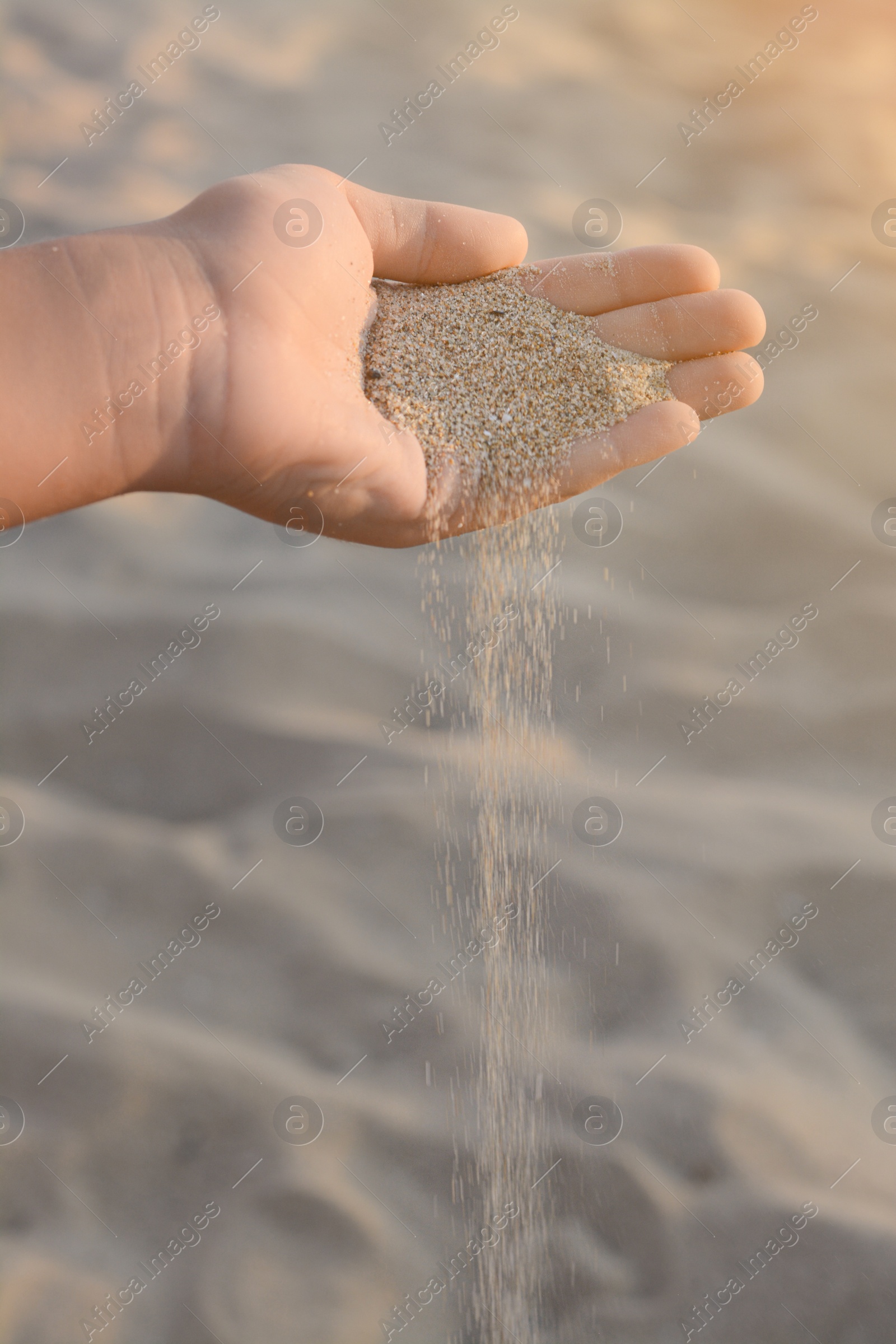 Photo of Girl pouring sand from hand outdoors, closeup. Fleeting time concept