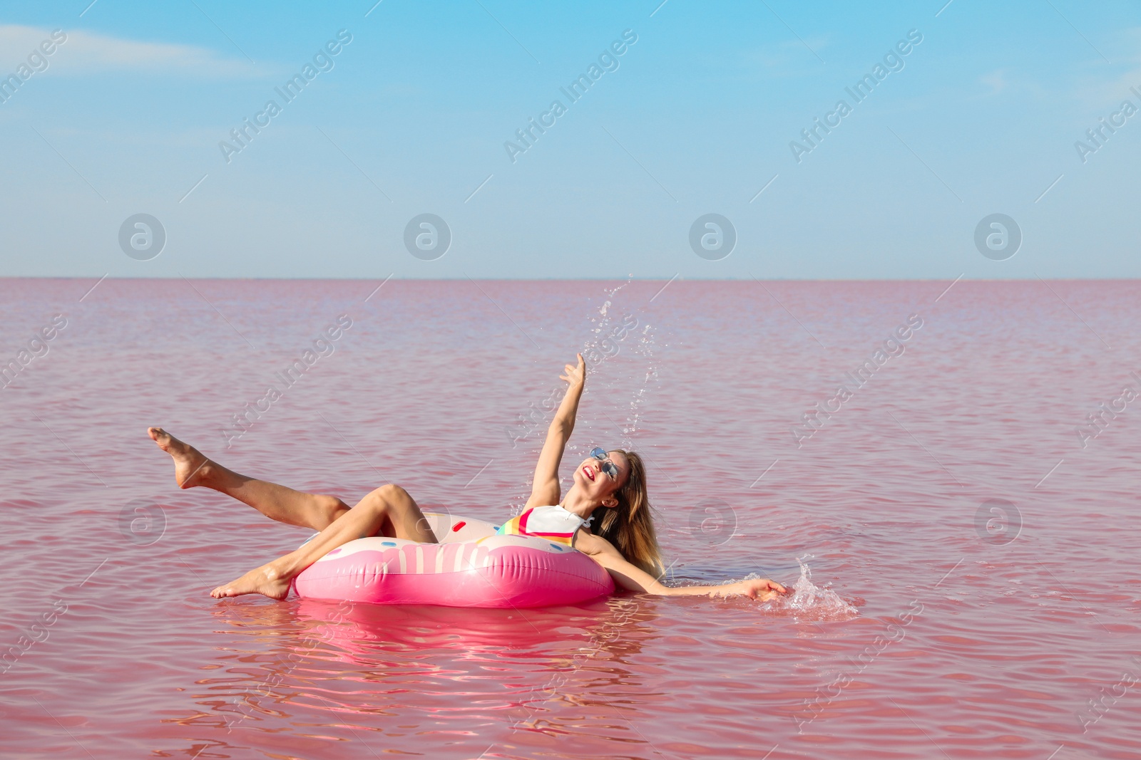 Photo of Beautiful woman on inflatable ring in pink lake