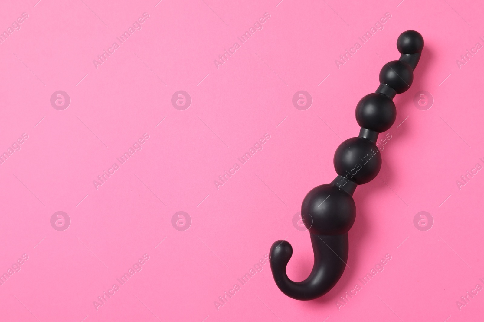 Photo of Black anal ball beads on pink background, top view with space for text. Sex toy