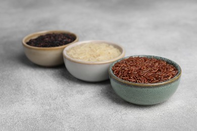 Photo of Bowls with different sorts of rice on grey table