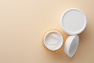 Photo of Jars of face cream on beige background, flat lay. Space for text