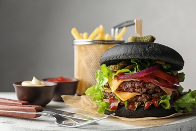 Photo of Black burger served on board. Space for text