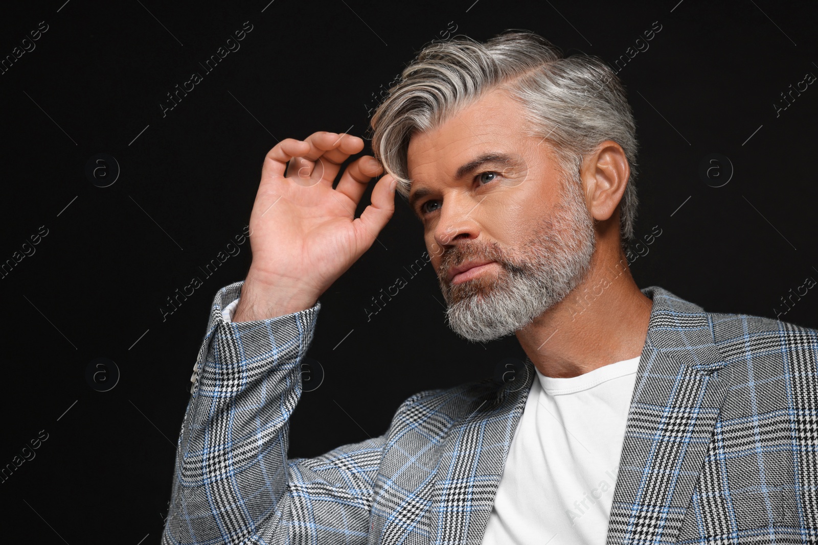 Photo of Portrait of confident man with beautiful hairstyle on black background