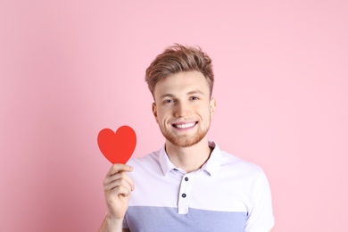 Photo of Portrait of young man with paper heart on color background