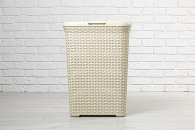 Photo of Empty laundry basket near white brick wall