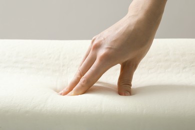 Woman touching orthopedic memory foam pillow, closeup