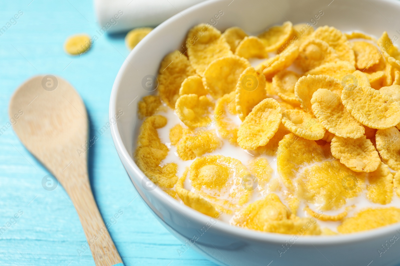 Photo of Tasty crispy corn flakes with milk on light blue table, closeup