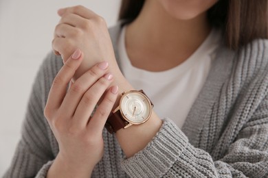 Woman with luxury wristwatch on light background, closeup