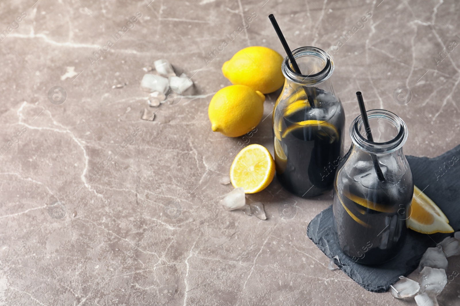 Photo of Bottles with natural black lemonade on grey background