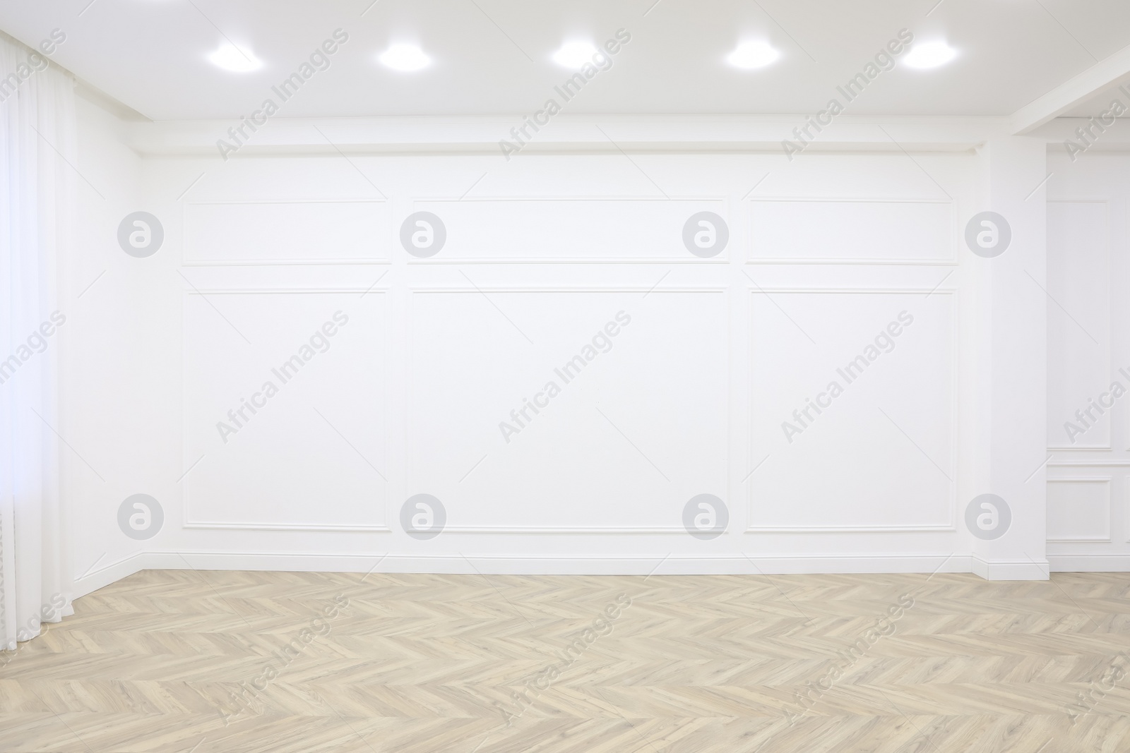 Photo of Empty room with white wall, wooden floor and spot lamps on ceiling