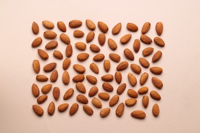 Photo of Delicious raw almonds on beige background, flat lay
