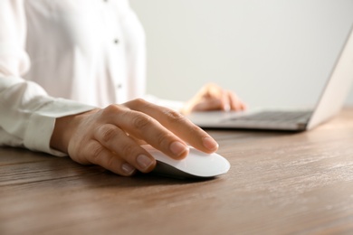 Woman using computer mouse with laptop at table, closeup