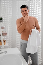 Handsome man touching his smooth face in bathroom after shaving