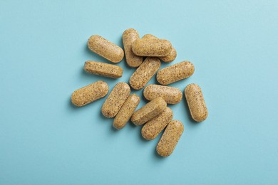 Dietary supplement pills on light blue background, flat lay