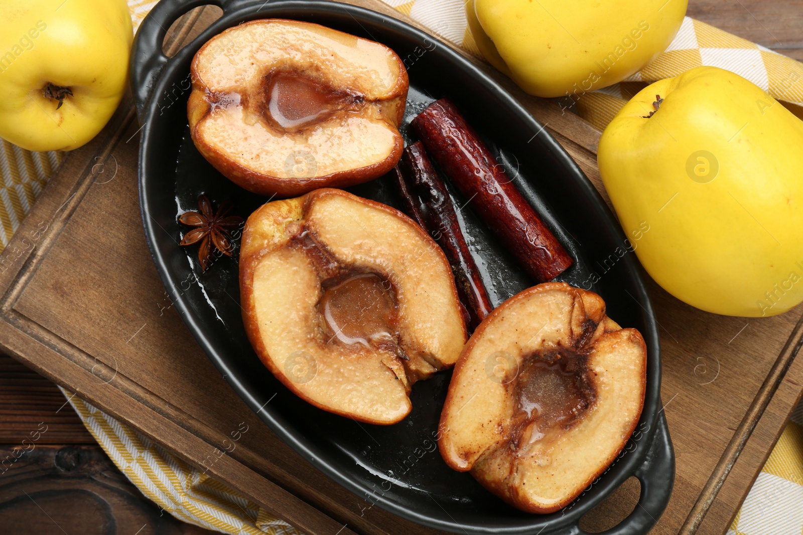 Photo of Tasty baked quinces with spices and honey in dish on wooden table, flat lay