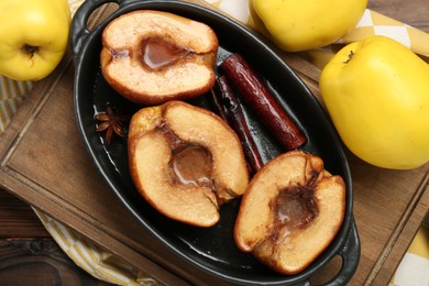 Photo of Tasty baked quinces with spices and honey in dish on wooden table, flat lay