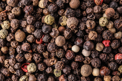 Photo of Pepper grains mix as background, top view