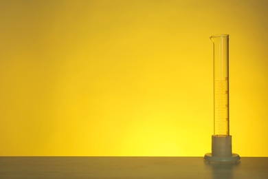 Photo of Empty graduated cylinder on table against color background. Chemistry laboratory glassware