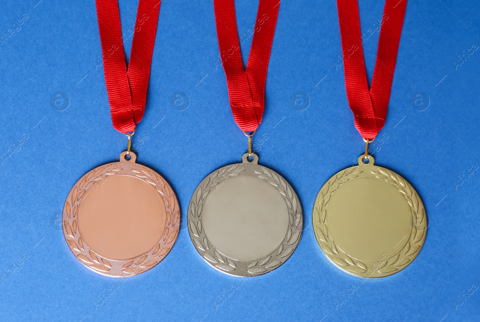 Photo of Gold, silver and bronze medals on blue background, flat lay. Space for design