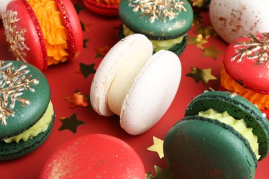 Photo of Beautifully decorated Christmas macarons and confetti on red background, closeup