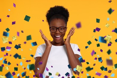 Image of Happy woman in glasses under falling confetti on orange background