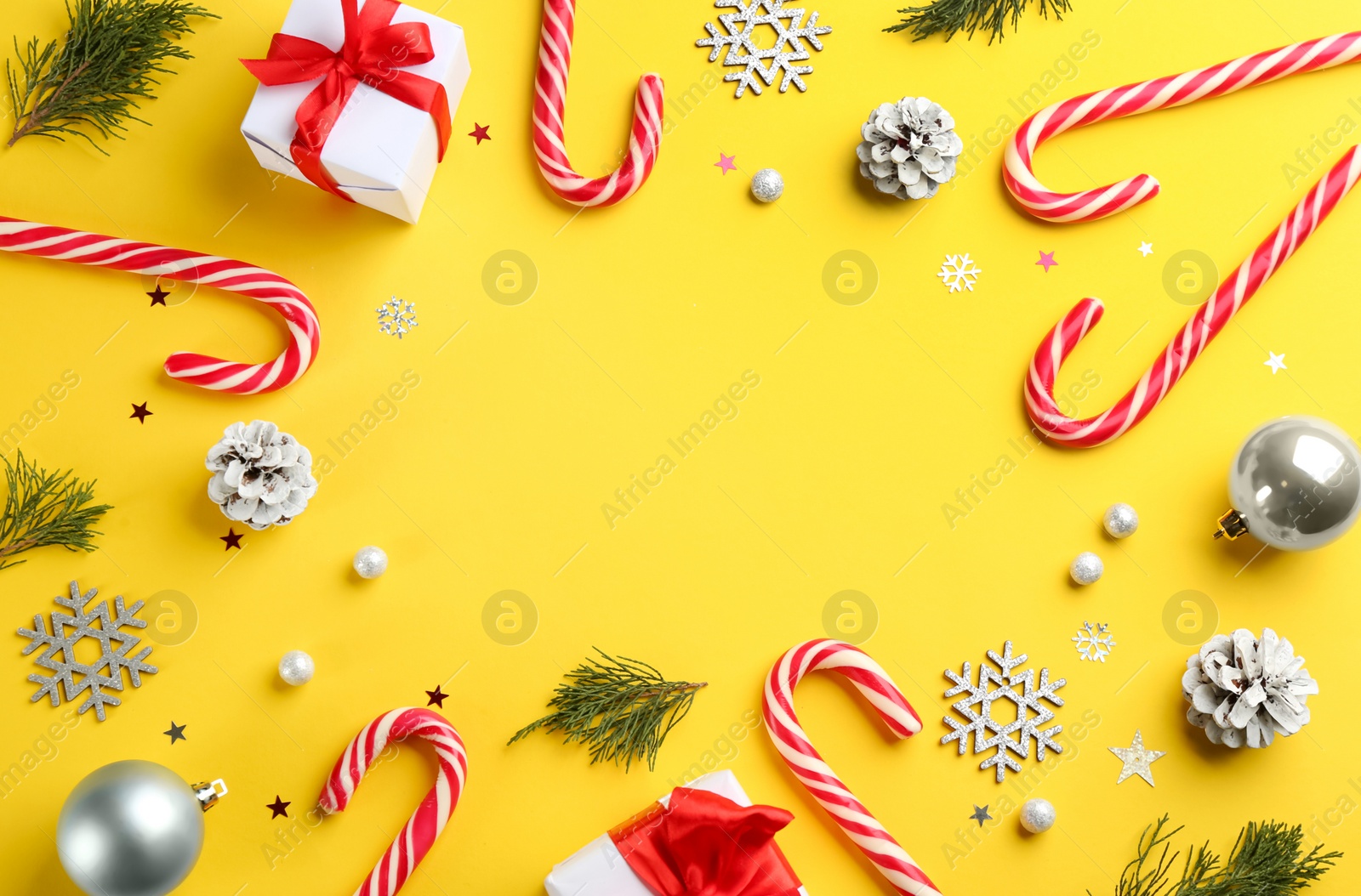 Photo of Frame of candy canes and Christmas decor on yellow background, flat lay. Space for text