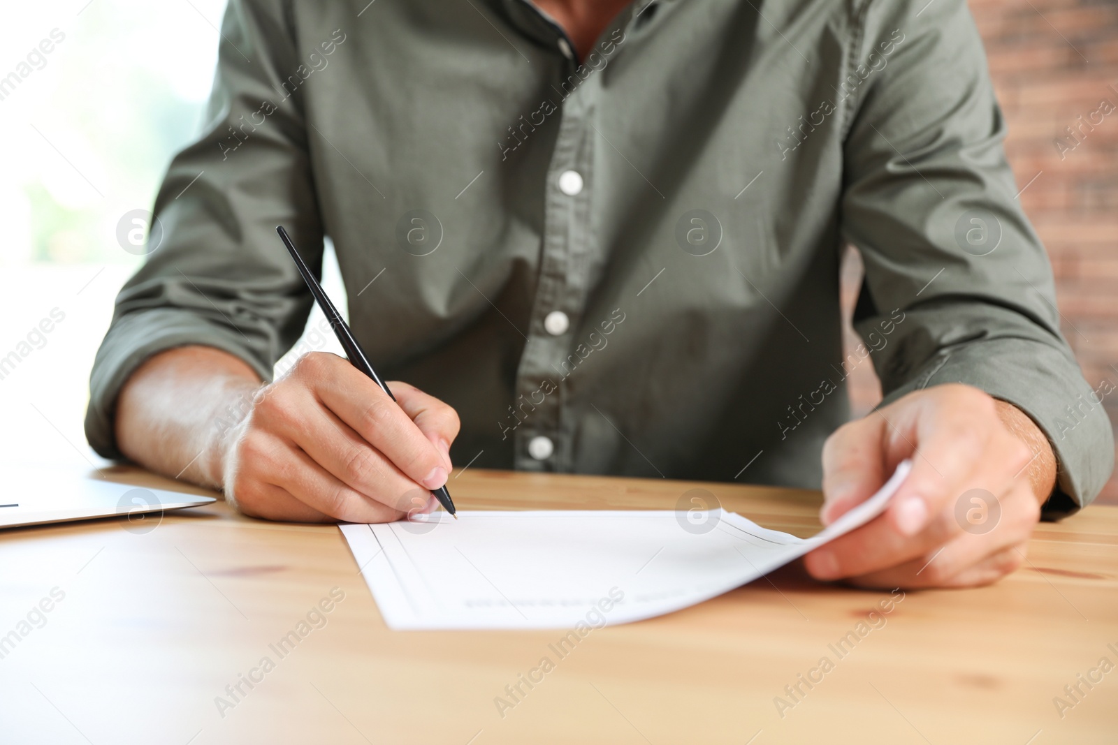 Photo of Male notary signing document at table in office, closeup