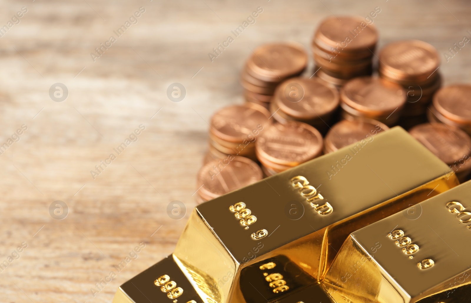 Photo of Shiny gold bars and coins on table. Space for text