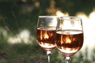 Photo of Glassestasty rose wine on blurred background, closeup and space for text. Picnic season