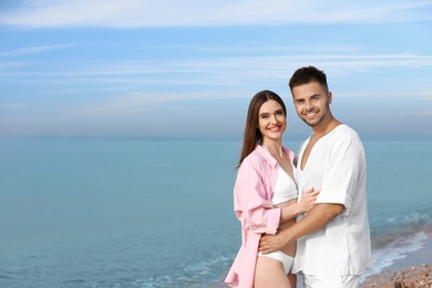 Young woman in bikini with her boyfriend on beach, space for text. Lovely couple