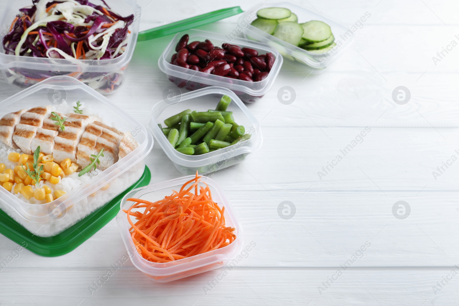 Photo of Set of plastic containers with fresh food on white wooden table, space for text