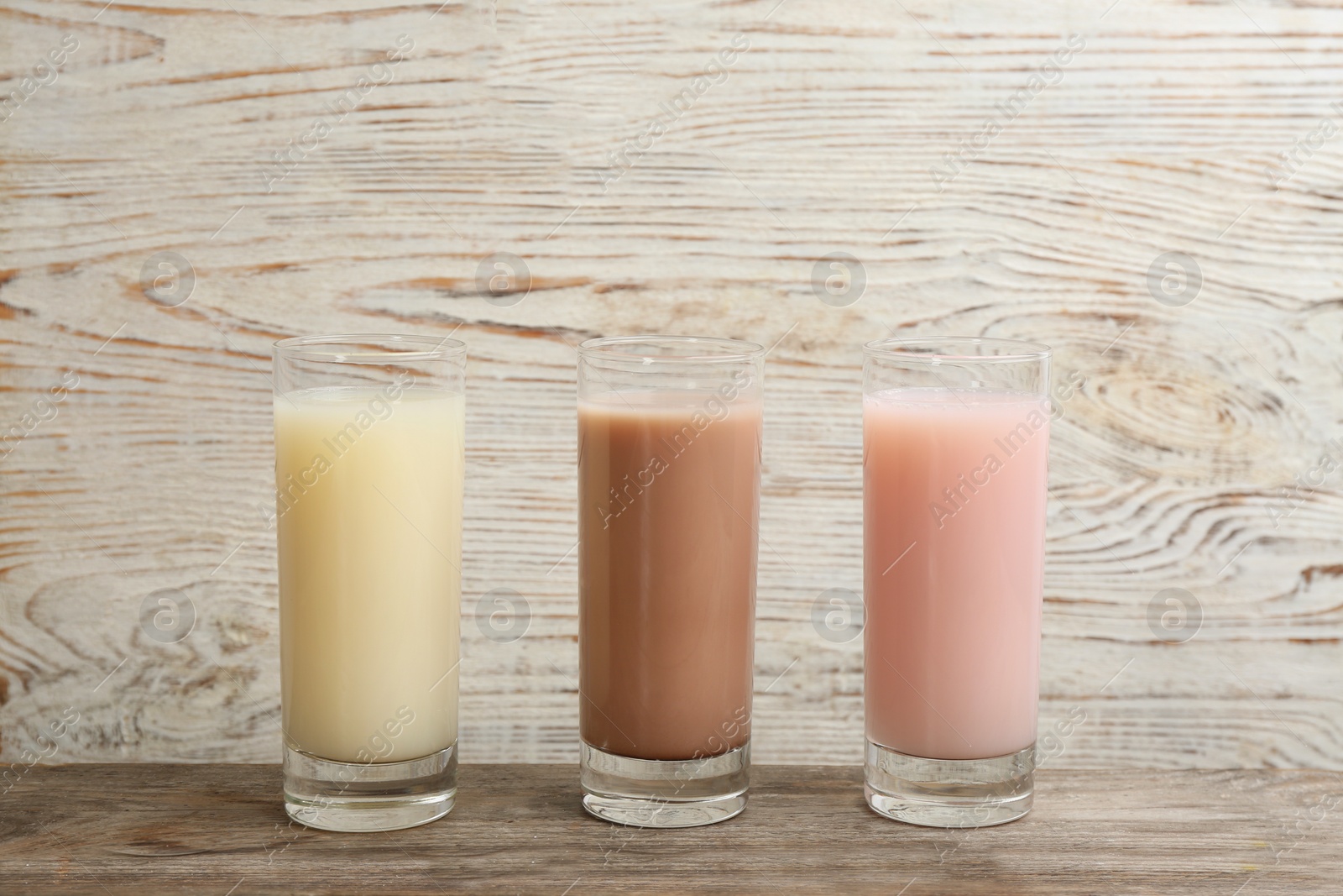 Photo of Different protein shakes in glasses on wooden table