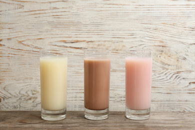 Photo of Different protein shakes in glasses on wooden table