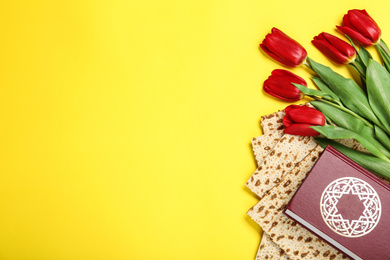 Photo of Tasty matzos, Torah and flowers on yellow background, flat lay with space for text. Passover (Pesach) Seder