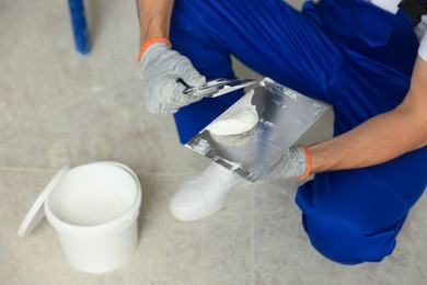 Photo of Worker with putty knife putting plaster on float, closeup