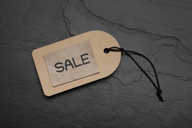 Photo of Tag with word Sale on dark stone table, top view. Black Friday