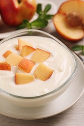 Photo of Delicious yogurt with fresh peach on light wooden table, closeup