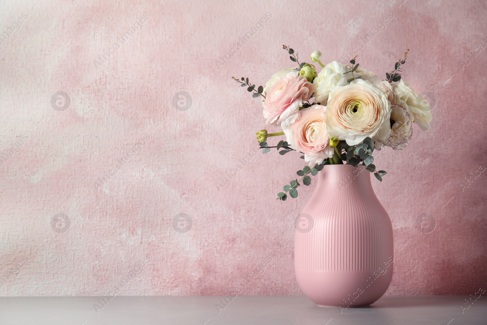 Photo of Vase with beautiful spring ranunculus flowers on table, space for text