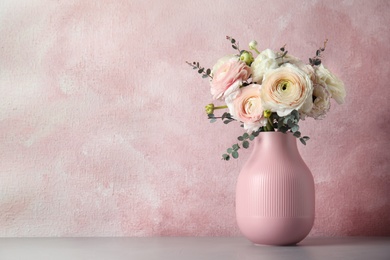 Vase with beautiful spring ranunculus flowers on table, space for text