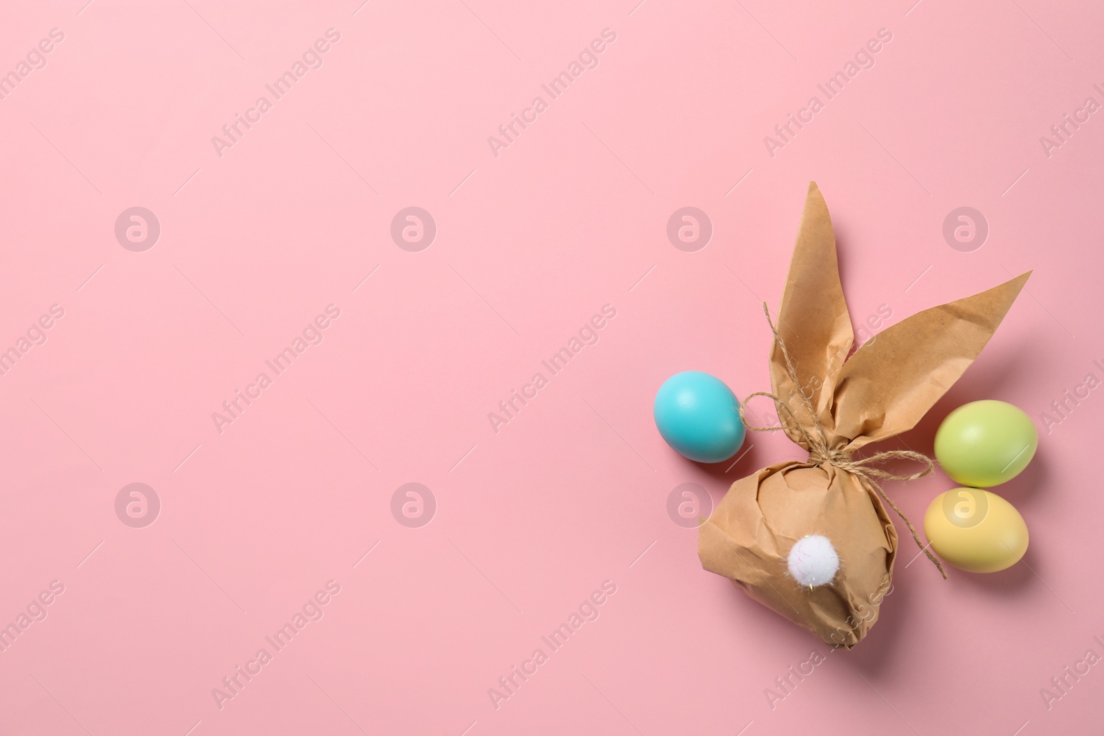 Photo of Flat lay composition of Easter bunny gift bag and dyed eggs on color background. Space for text