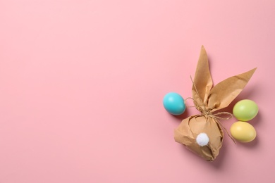 Flat lay composition of Easter bunny gift bag and dyed eggs on color background. Space for text