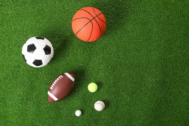 Photo of Many different sports balls on green grass, flat lay. Space for text